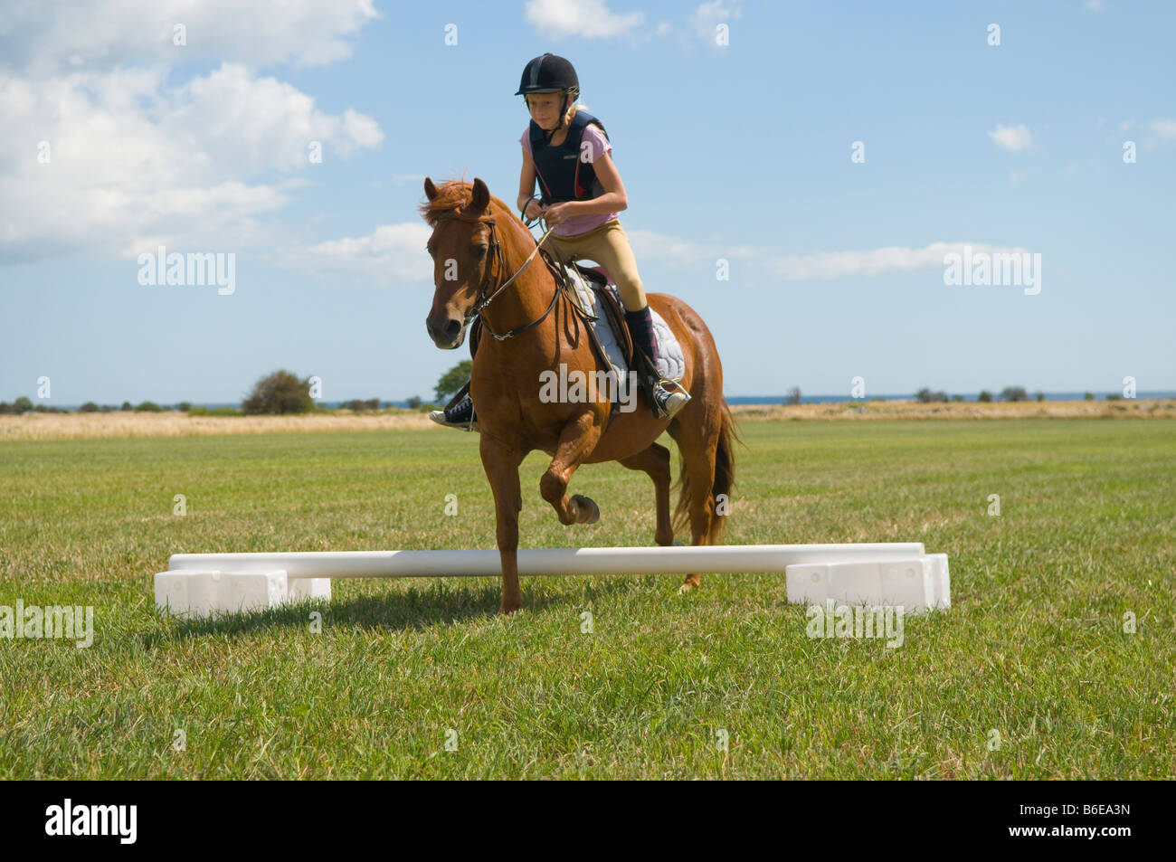 Mädchen ein Pony reiten auf einem Feld springen. Stockfoto