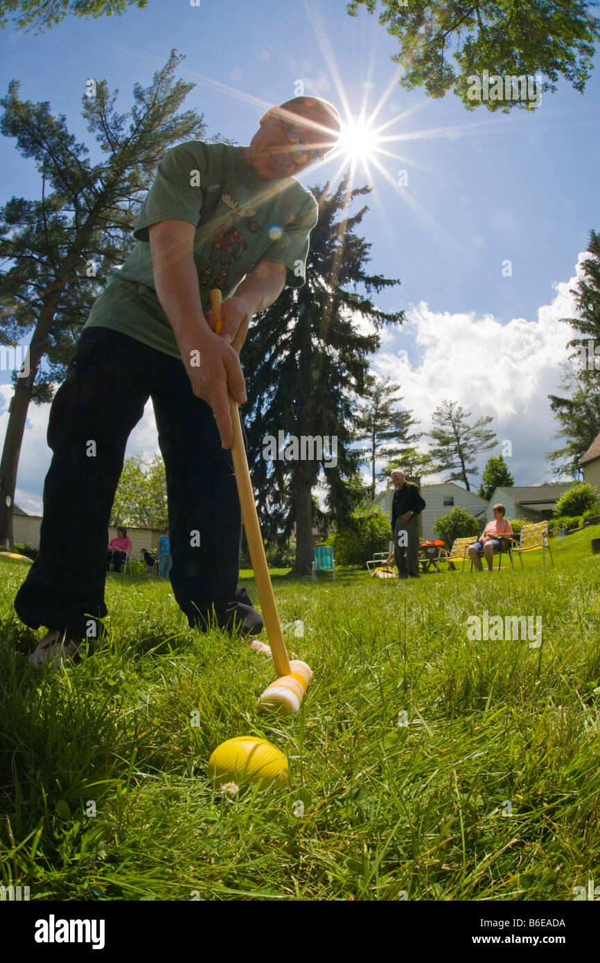 Niedrigen Winkel fisheye Sicht des Menschen, Krocket-Ball mit einem Krocket-Hammer mit der Sonne am Himmel hinter ihm Stockfoto