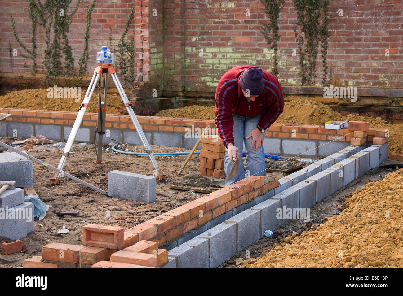 Legen zwei Reihen von Ziegelsteinen am Anfang der ersten Zeile von Betonsteinen, bereit ist, die Balken für den Boden zu legen, Stockfoto