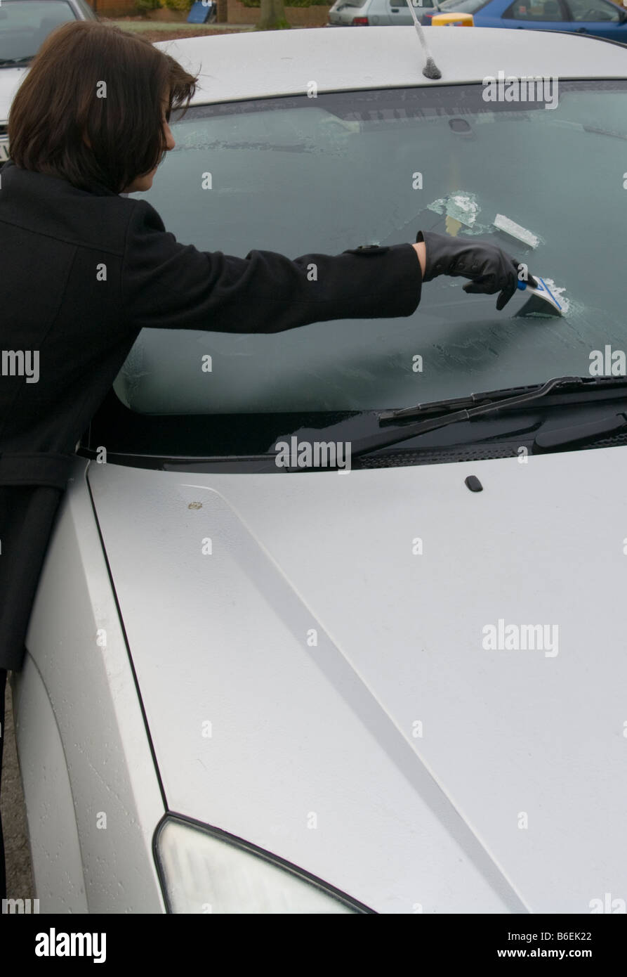 Frau Person kratzen Eis aus einem Autofenster Windschutzscheibe an einem frostigen Morgen Stockfoto