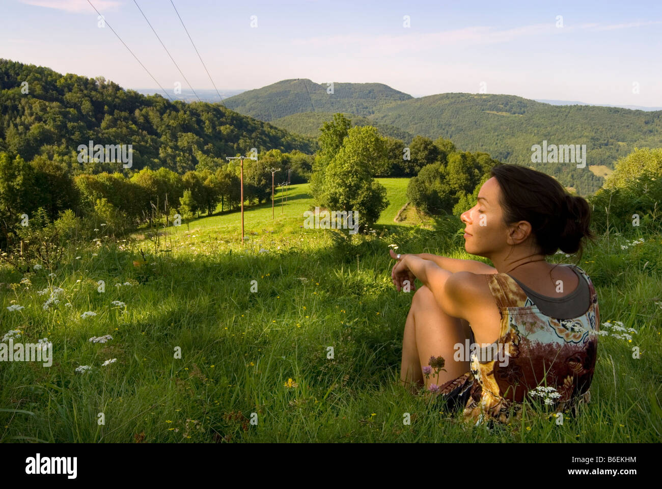 Junge Frau sitzt in dem langen Rasen von den französischen Pyrenäen. Stockfoto