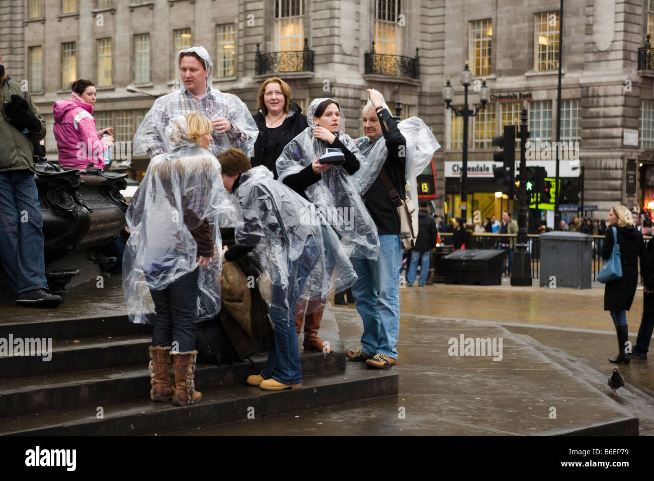 Gruppe von Touristen in London alle tragen die gleiche Art von Regenmantel Stockfoto