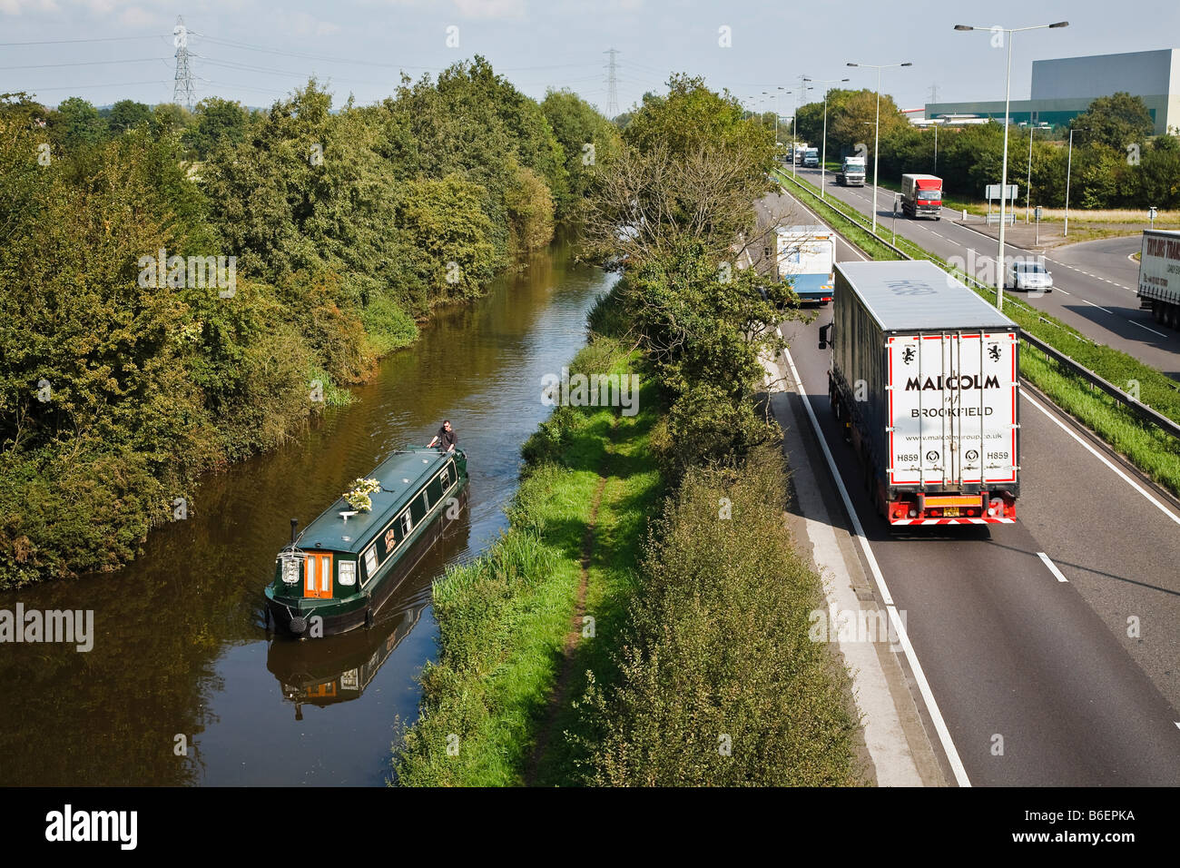 Hohen Verkehrsaufkommens auf der A38 kontrastiert mit einem Narrowboat gemächlich seinen Weg entlang der Trent und Mersey Kanal in der Nähe von Burton. Stockfoto