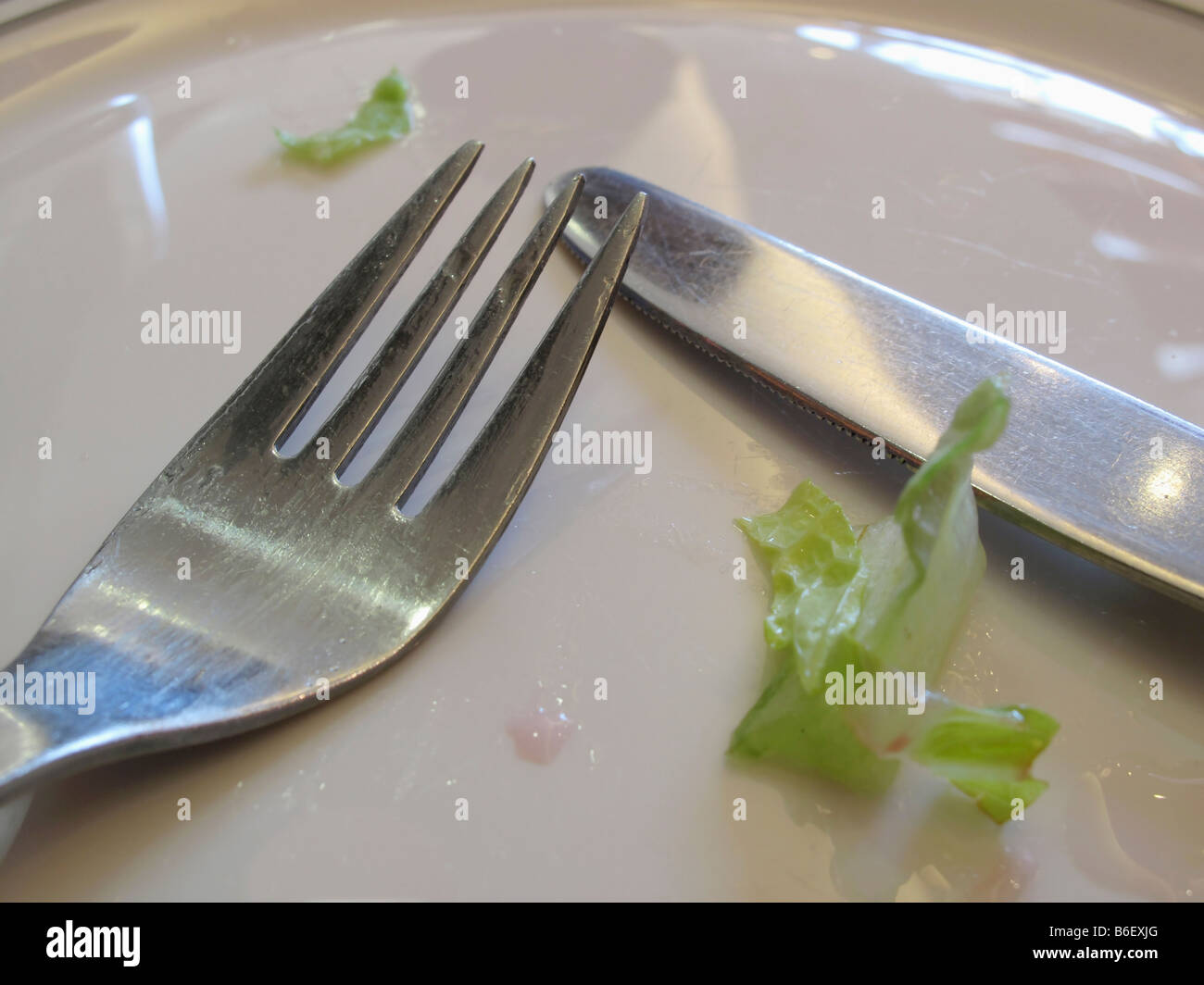 Messer und Gabel auf leeren Teller nach einer Mahlzeit Stockfoto