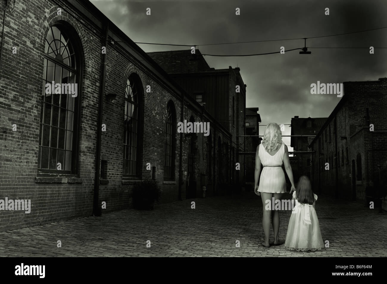 Frau und ein Kind in eine dunkle leere Straße Stockfoto