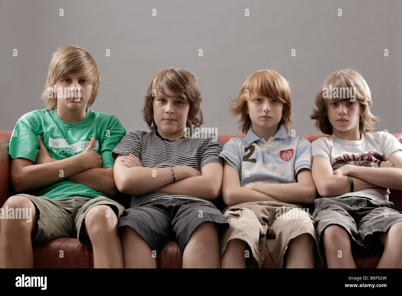 Vier Jungs mit Armen gefalteten sitzen auf einem sofa Stockfoto