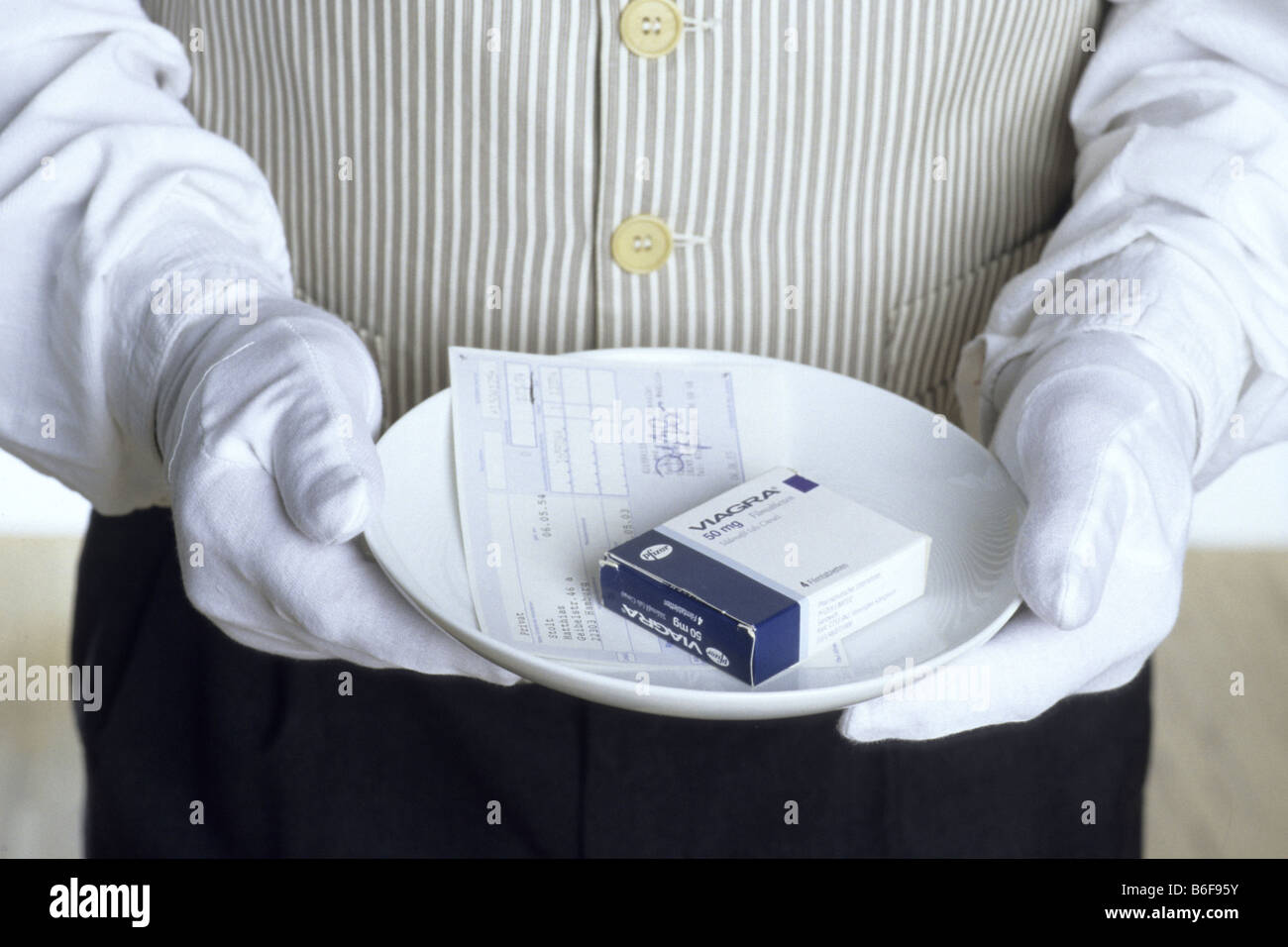 Butler mit weißen Handschuhen Halteplatte mit Viagra-box Stockfoto