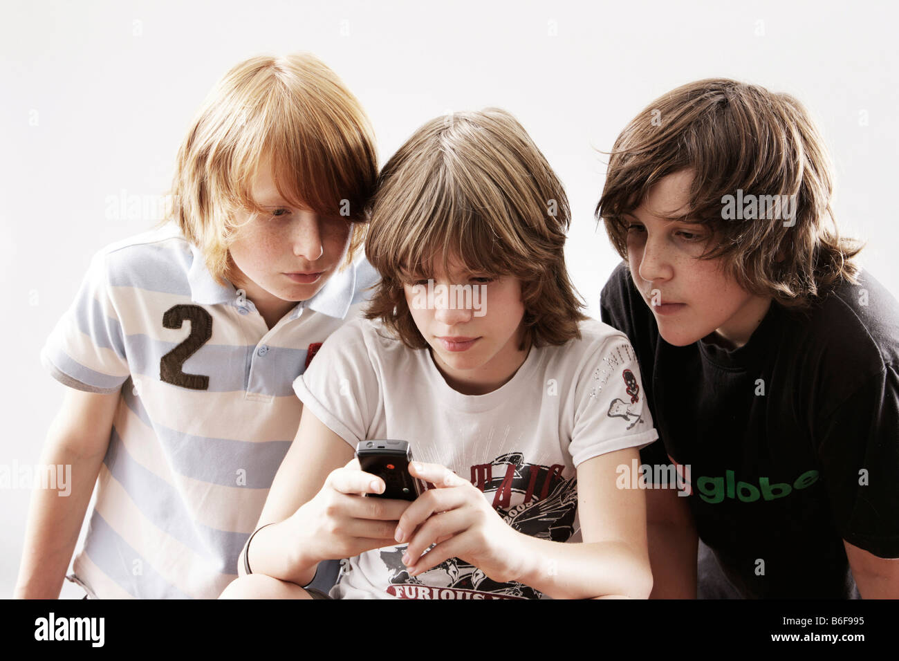 Drei Jungs spielen mit einem Handy Stockfoto
