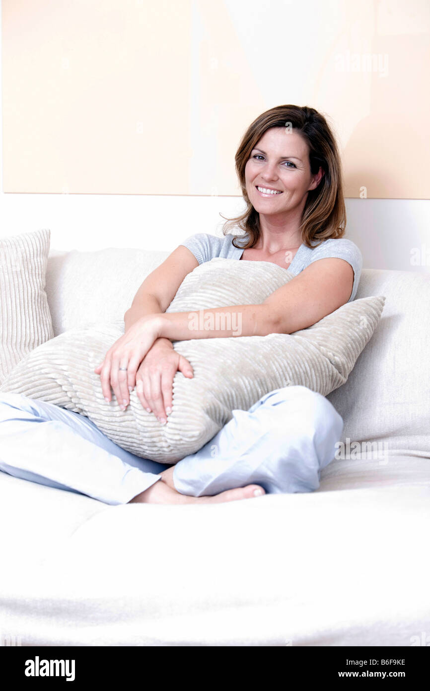 Frau hält ein Polster und sitzen auf einem sofa Stockfoto