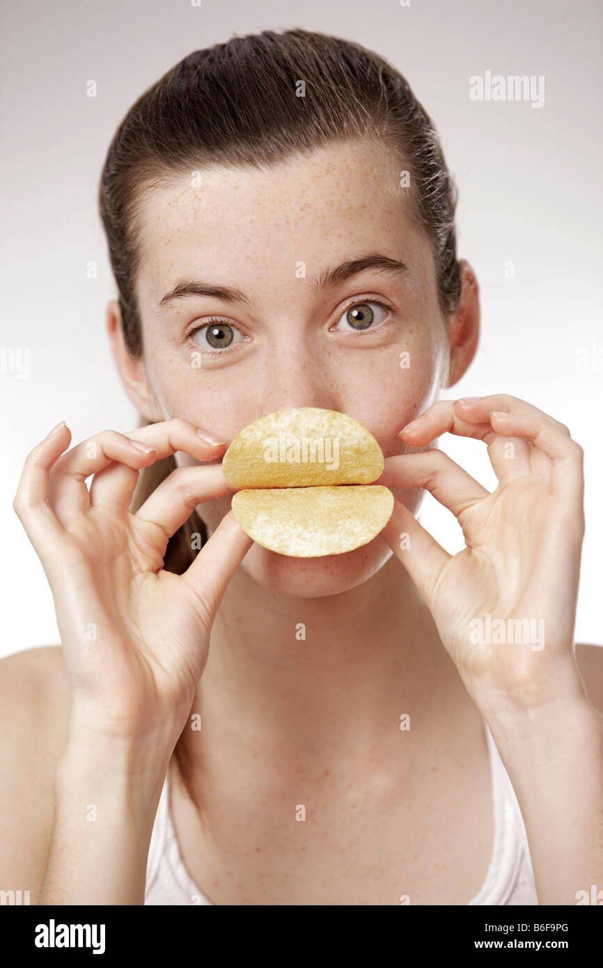 Teenager-Mädchen, Frau, 17 Jahre alt, Holding Chips als Lippen vor den Mund Stockfoto