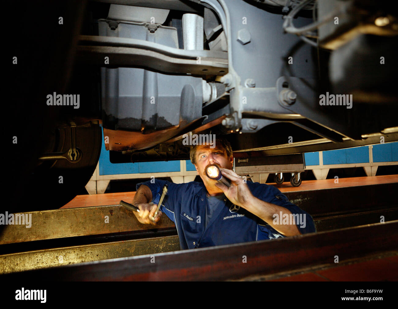 Mechaniker mit einer Taschenlampe im Motorraum eines LKW in der Nutzfahrzeug-Werkstatt von der Daimler AG, Merce inspizieren Stockfoto