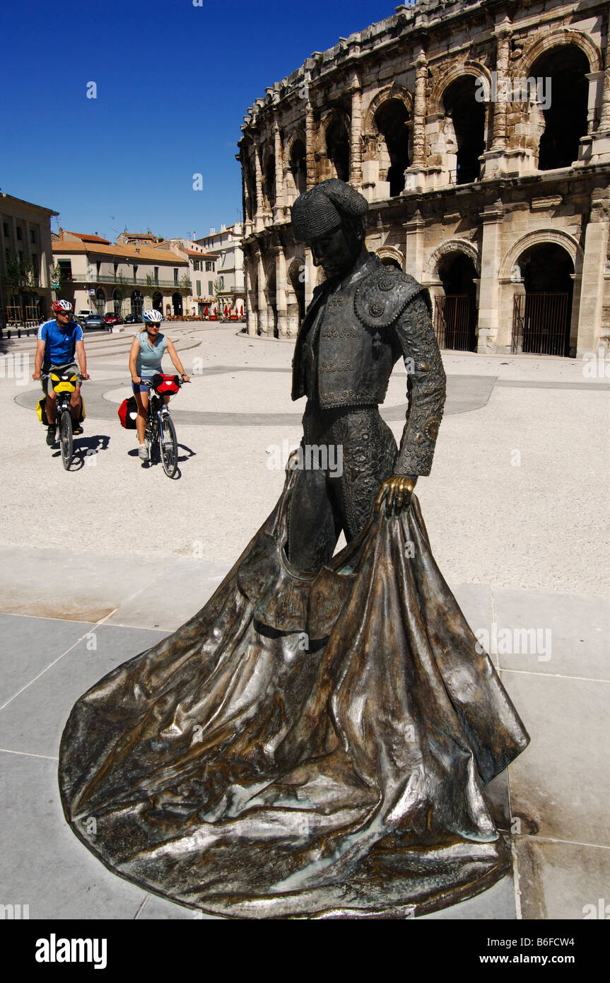 Radfahrer hinter die Bronzestatue der Bull Fighter Christian Montcouquiol, El Nimeno II, vor der Arena, die Nimes ein Stockfoto