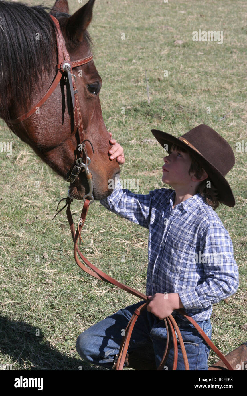 Ein junger Cowboy streicheln sein Pferd auf der ranch Stockfoto