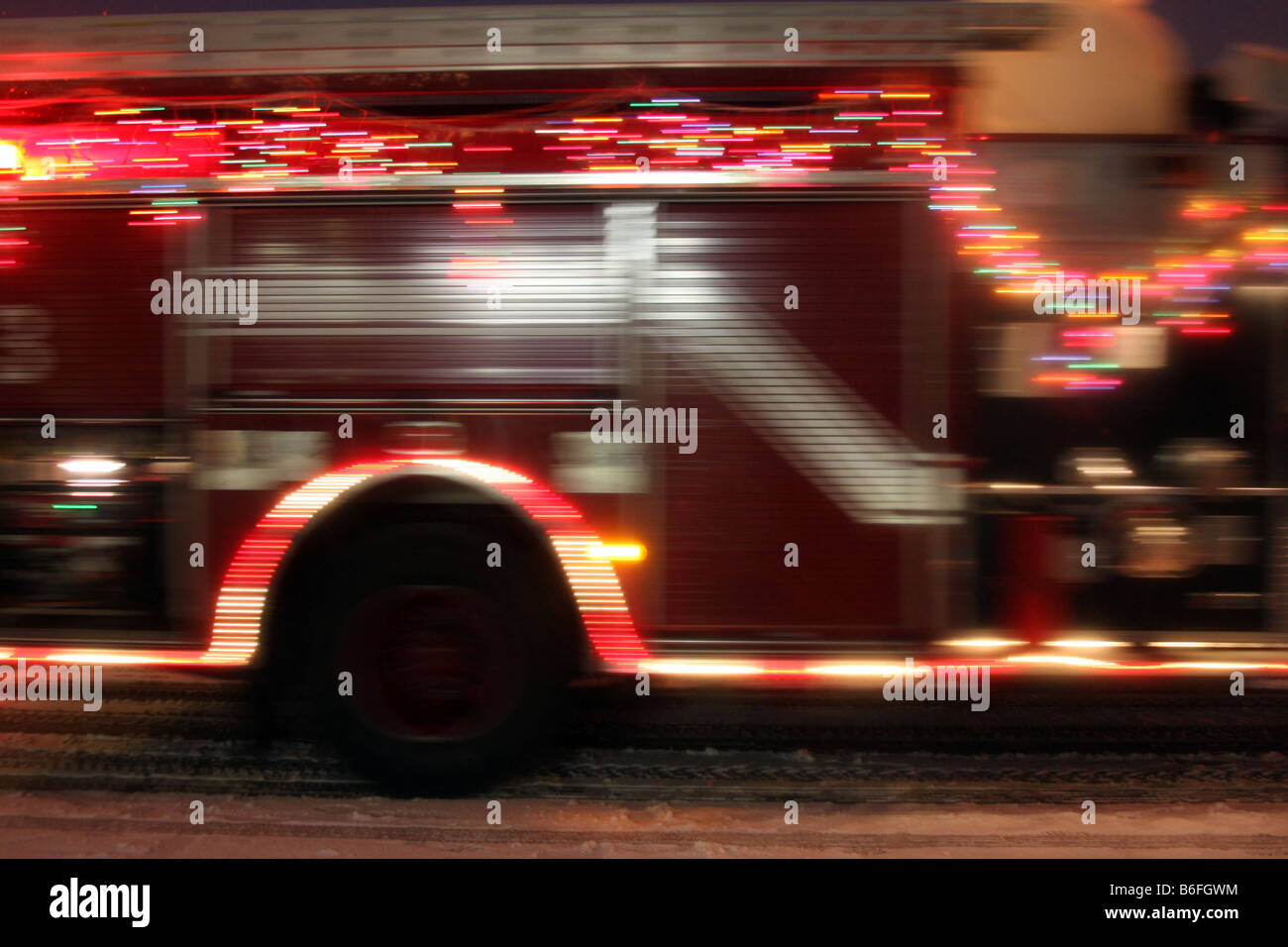 Die Unschärfe ein Feuerwehrauto alle dekoriert mit Weihnachtsbeleuchtung in einer Parade während eines Schneesturms Stockfoto