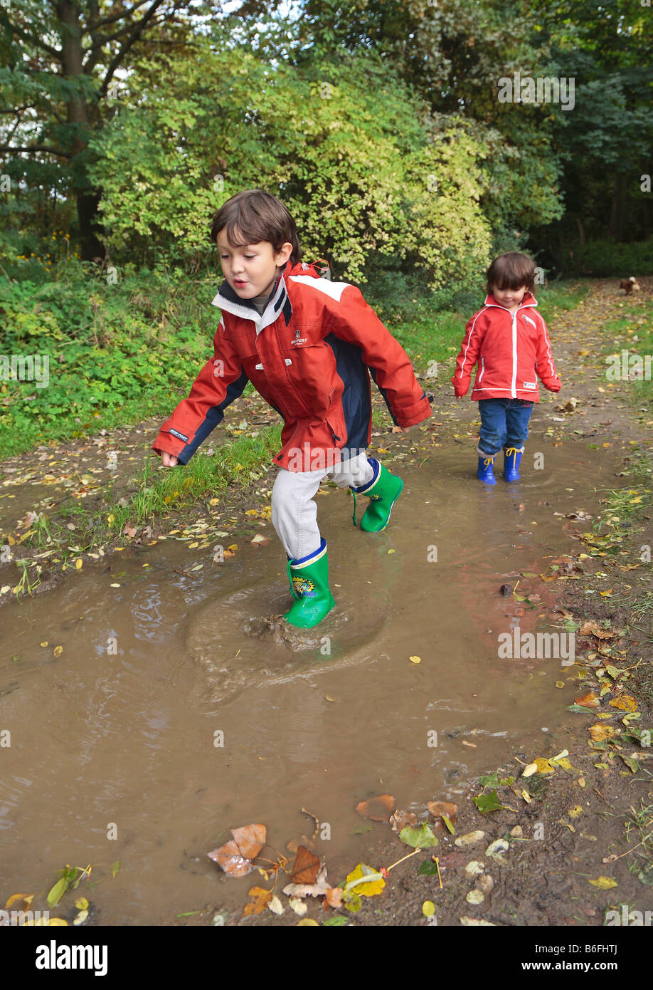 Kinder tragen Gummistiefel zu Fuß durch Pfützen, Niederwerth, Rheinland-Pfalz, Deutschland, Europa Stockfoto