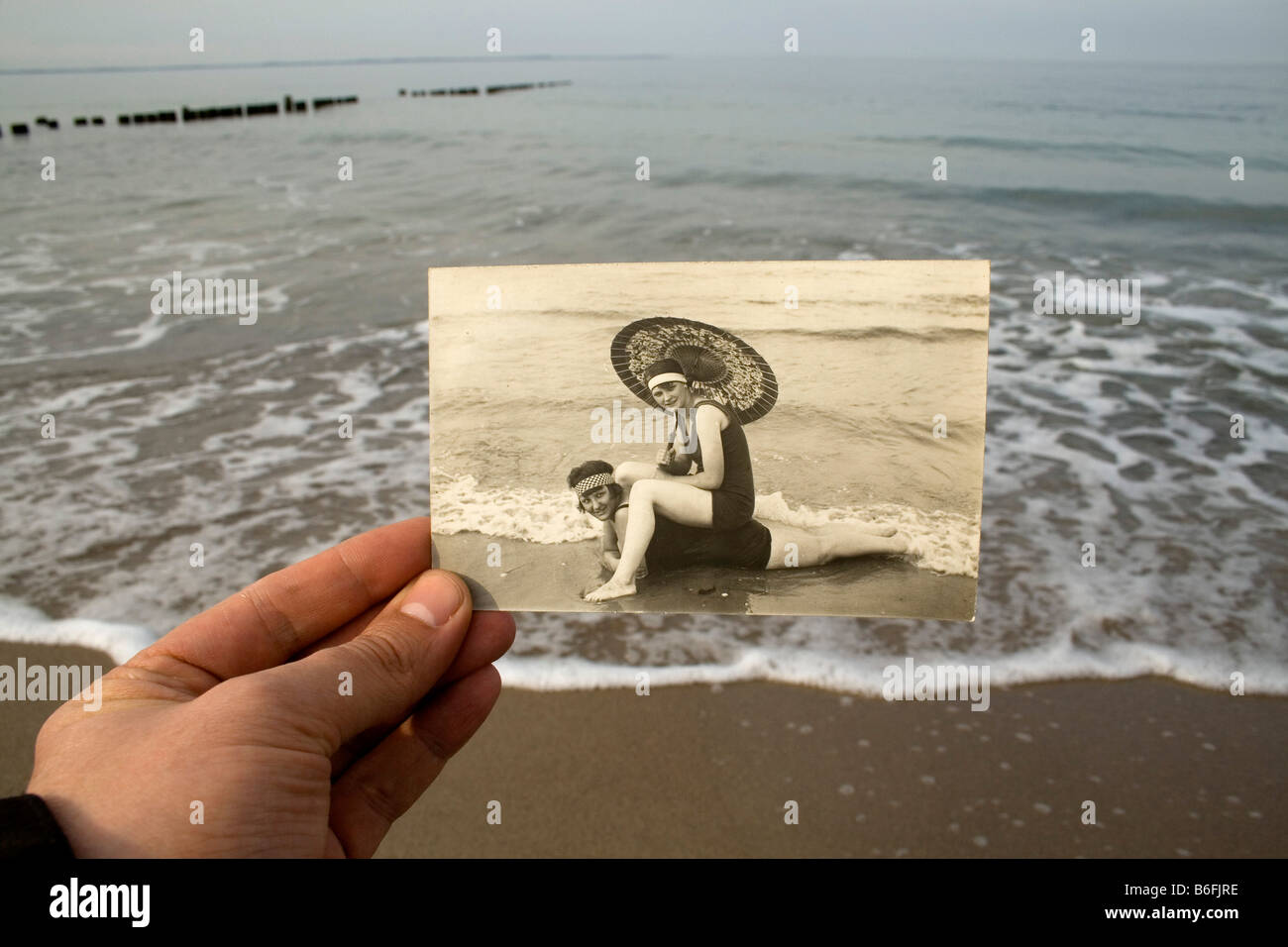 Hand mit einer Postkarte, ca. 1920, vor der Ostsee, damals und heute Stockfoto
