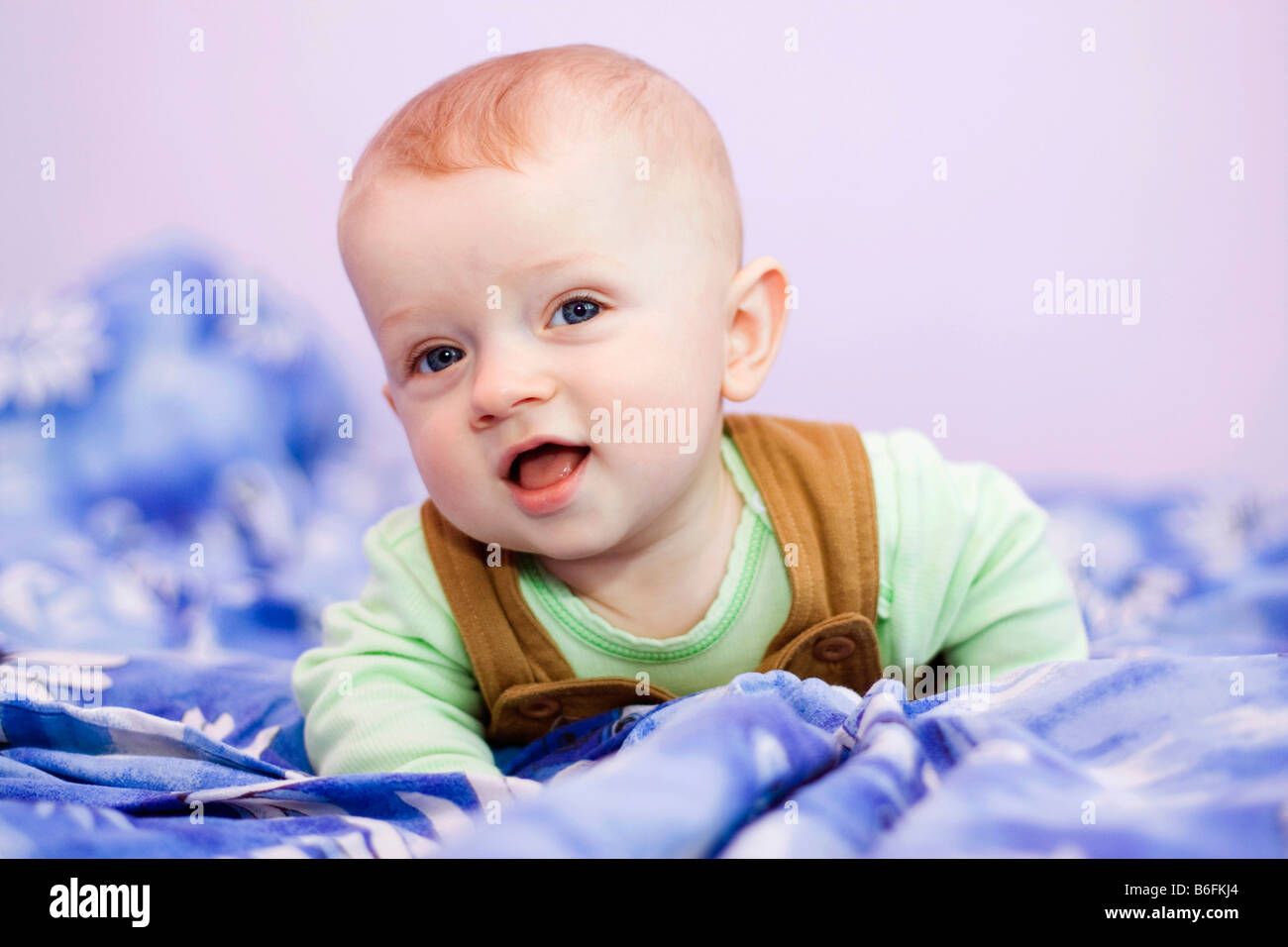 Lächelnden jungen, 7 Monate alt, auf einem Bett Stockfoto