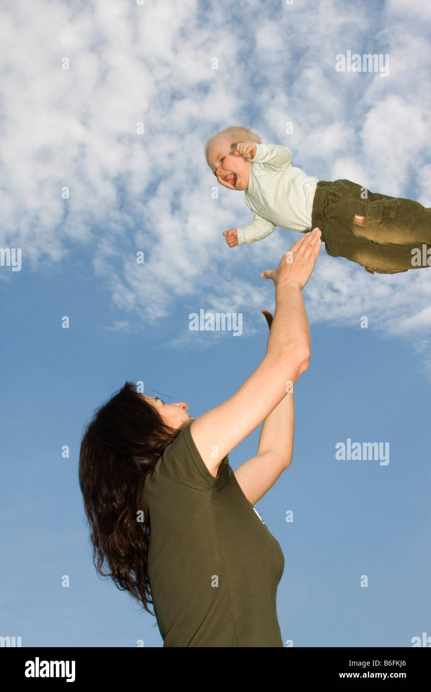 Mutter, 32 Jahre alt, und ihre fliegenden Babymädchen, 9 Monate alt, außerhalb Stockfoto