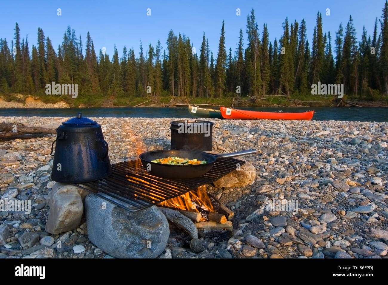 Topf, Pfanne, Kochen am Lagerfeuer, Kanus hinter Kiesbank, Liard River, British Columbia, Yukon Territorium, Kanada, Nord bin Stockfoto