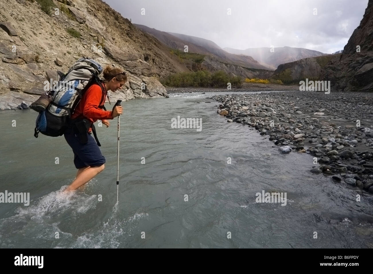 Junge Frau, Backpacker, Wanderer, waten durch Big Horn Creek, St. Elias Gebirge, Donjek Route, Kluane National Park, Yukon Te Stockfoto