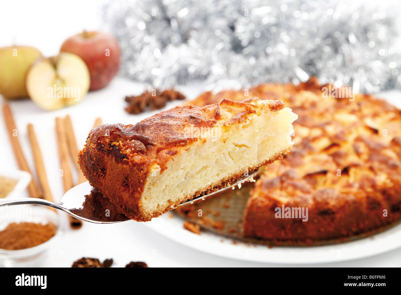 Weihnachts-Apfelkuchen mit frischen Äpfeln, Zimt, Stangen Zimt und Zucker auf einem Tortenheber Stockfoto