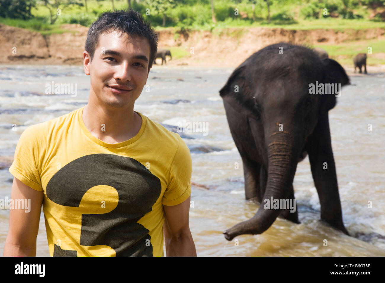 Ein Tourist, posiert für ein Foto vor einem Elefanten am Maha Oya Fluss in der Nähe von The Pinnawela-Elefantenwaisenhaus Stockfoto
