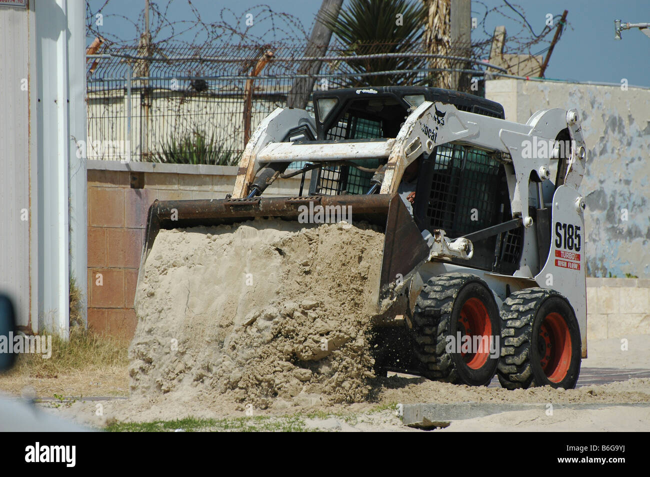 Israel Atlit Bauarbeiter mit einem Bobcat Typ Traktor Sand und Schutt zu löschen Stockfoto