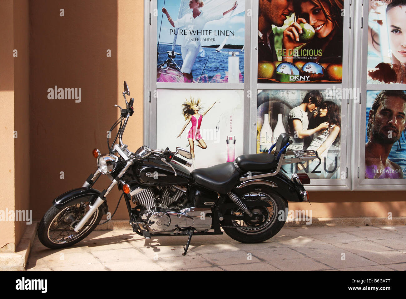 Altes Yamaha Motorrad geparkt neben einigen Werbetafeln in heller Sonne in Palma Nova, Mallorca. Stockfoto
