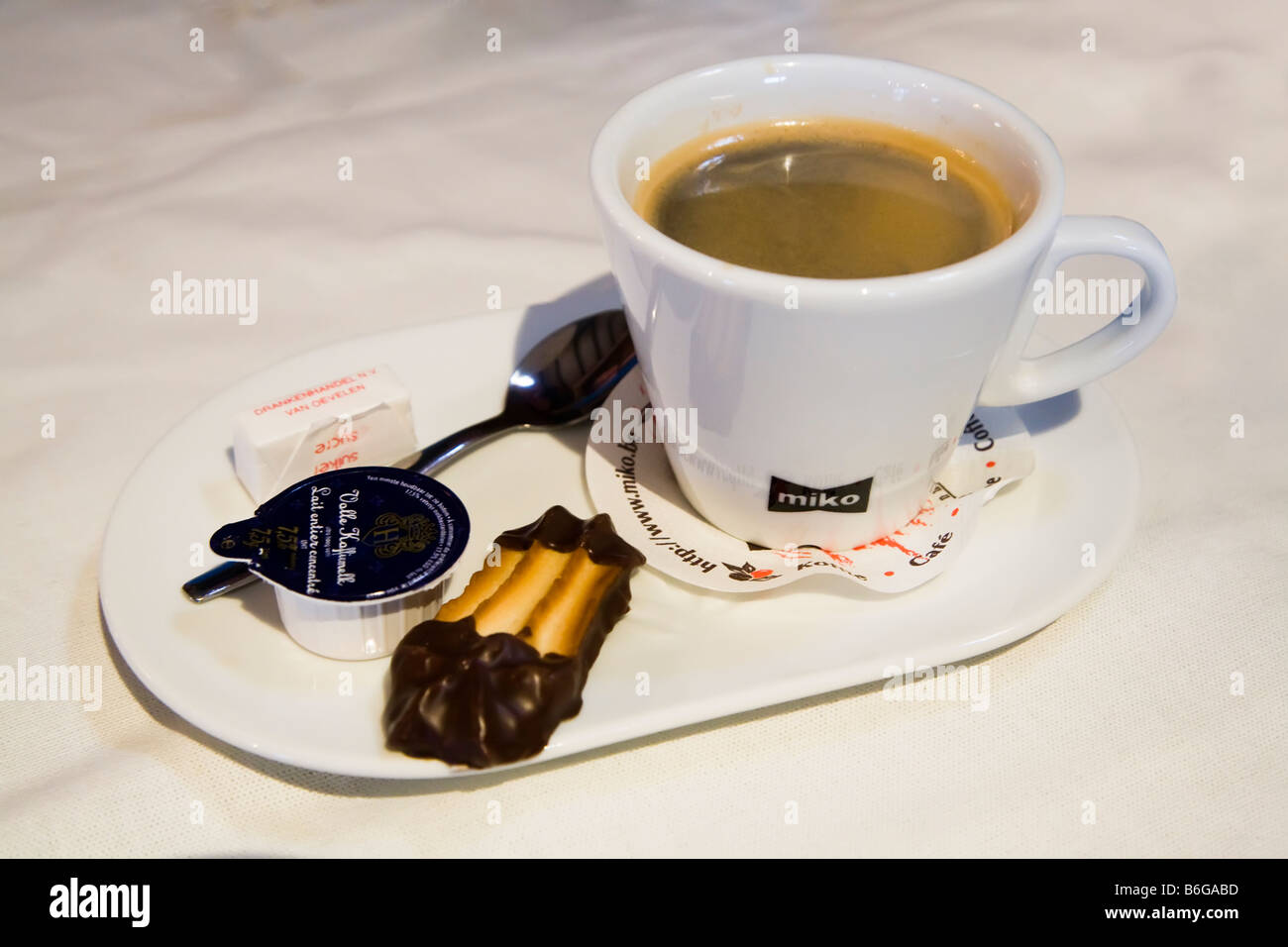 Tasse schwarzer Kaffee mit Milch und Kuchen auf Teller wie in Niederlande Café serviert Stockfoto