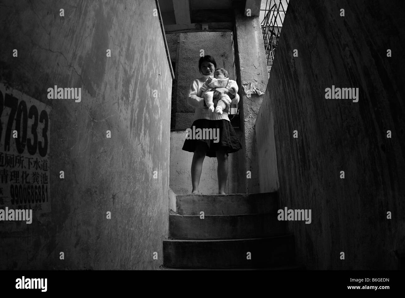 Chinesische Frau steht an Spitze der konkreten Treppenhaus tragen Minirock mit baby Stockfoto