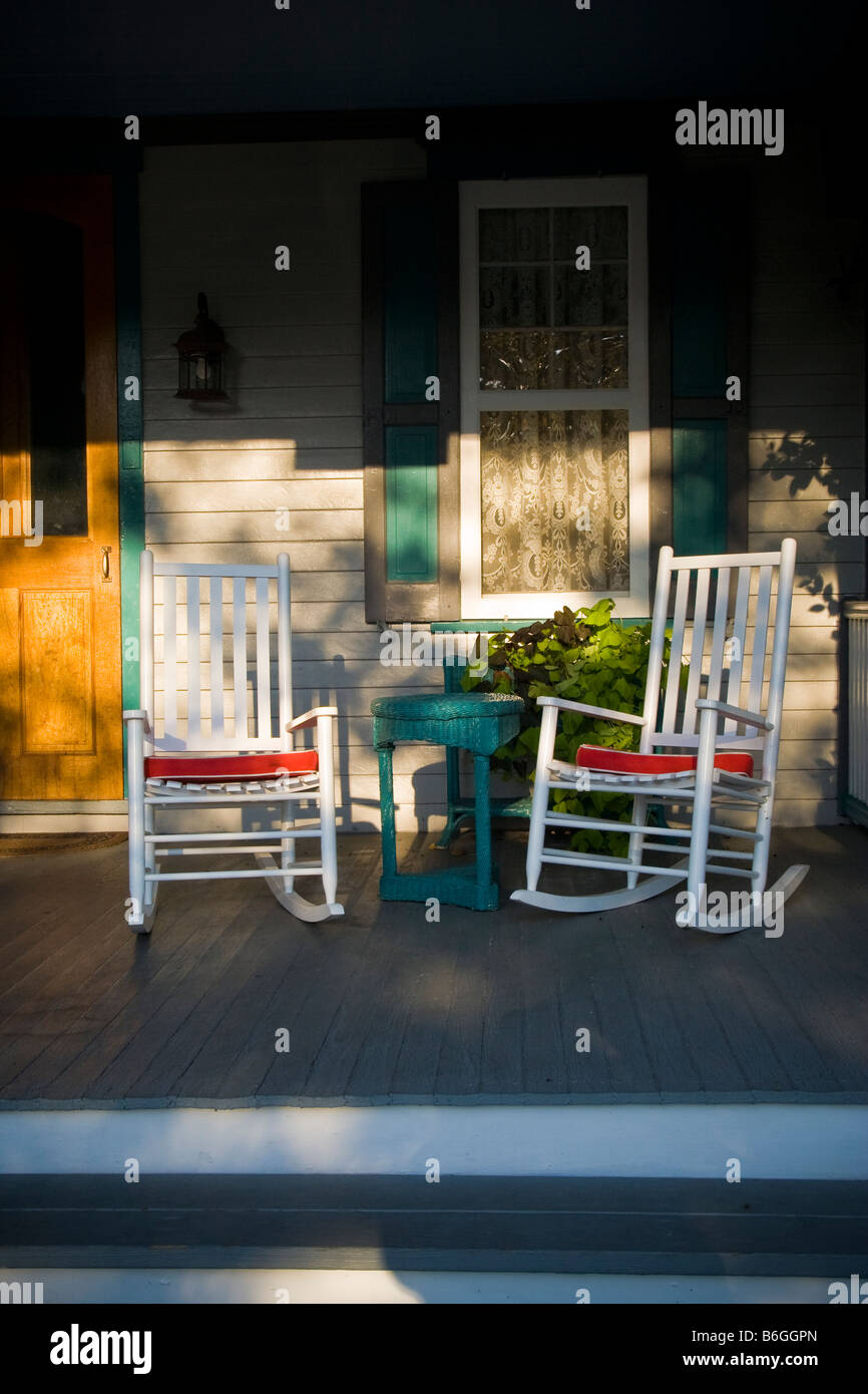 Abendsonne auf einem malerischen viktorianischen Veranda mit zwei Schaukelstühle und ein Fenster mit Gardinen. Stockfoto