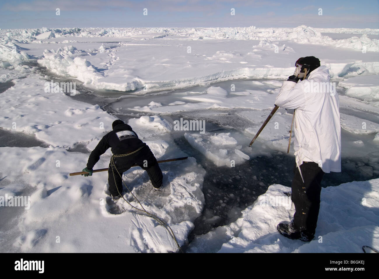 Inupiaq Walfänger öffnen ein Loch in das Packeis für potentielle Tierwelt Tschuktschensee passieren Stockfoto