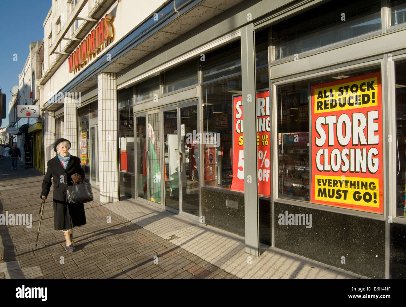 Eine ältere Dame geht es vorbei an der Schließung der Verkauf an einen Woolworths Shop. Stockfoto