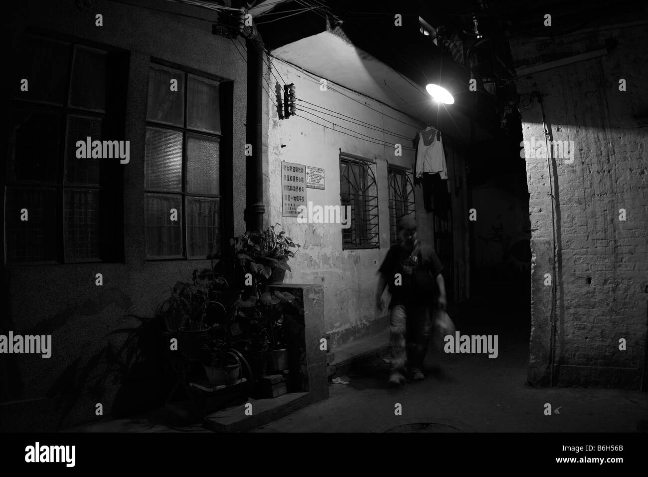 Abbildung Bewegung zu Fuß hinunter eine alte dunkel beleuchteten Ecke Allee vorbei an einer alten Lagerhalle im Schatten der obenliegenden Straßenlaternen in China Stockfoto