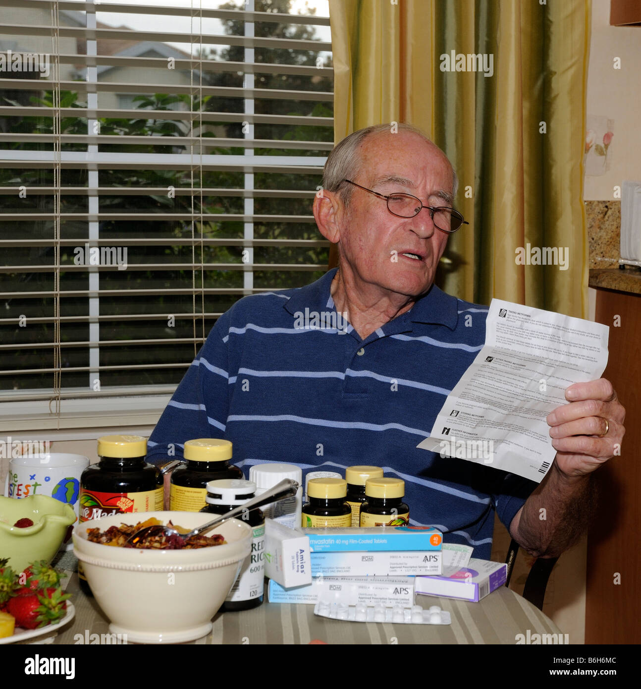 Mann am Frühstückstisch mit vorgeschriebenen Arzneimittelverordnung Informationen Hinweise zu betrachten. Stockfoto