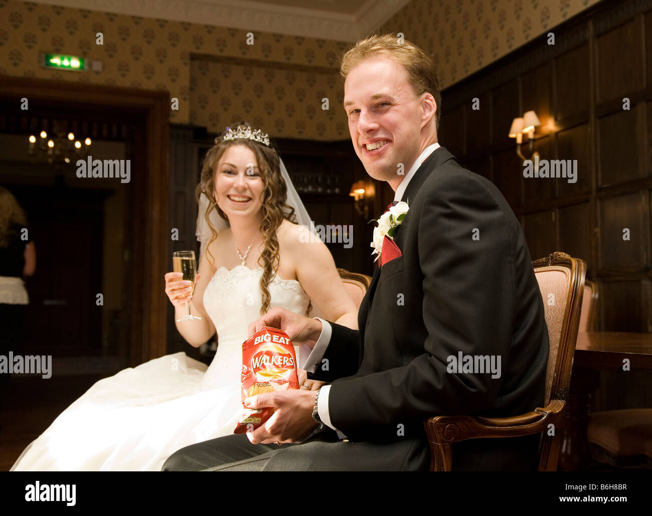 Braut & Bräutigam teilen eine Tasche von Walkers Chips auf ihrer Hochzeit Stockfoto