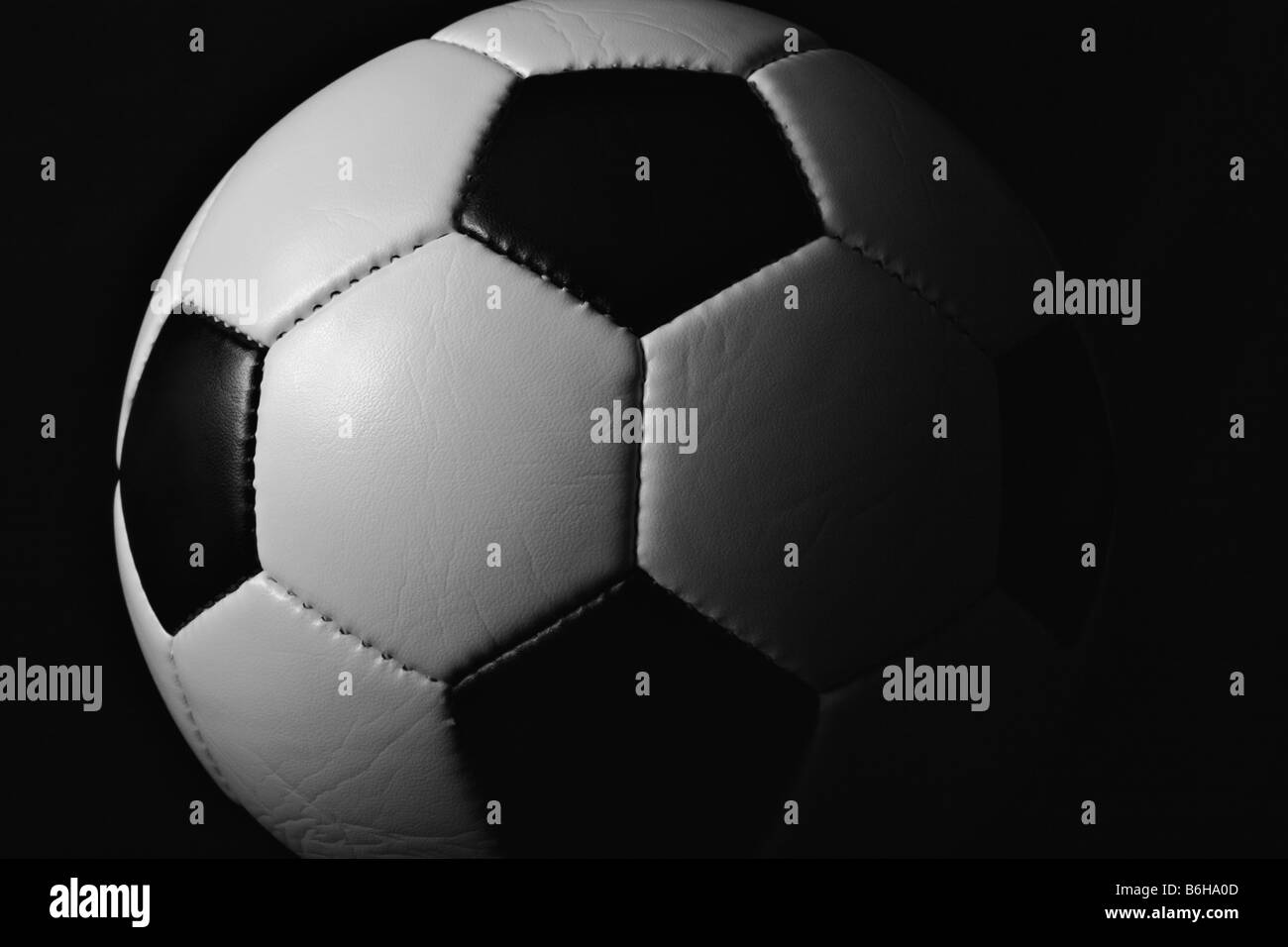 Schwarze und weiße Hälfte beleuchtet (beleuchteten) Fußball (Fußball) Ball close-up auf schwarzem Hintergrund. Stockfoto
