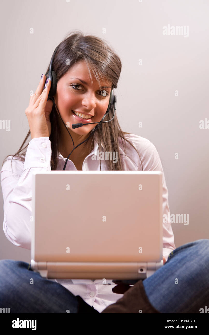 Junge Frau trägt Kopfhörer für einen Plausch mit laptop Stockfoto