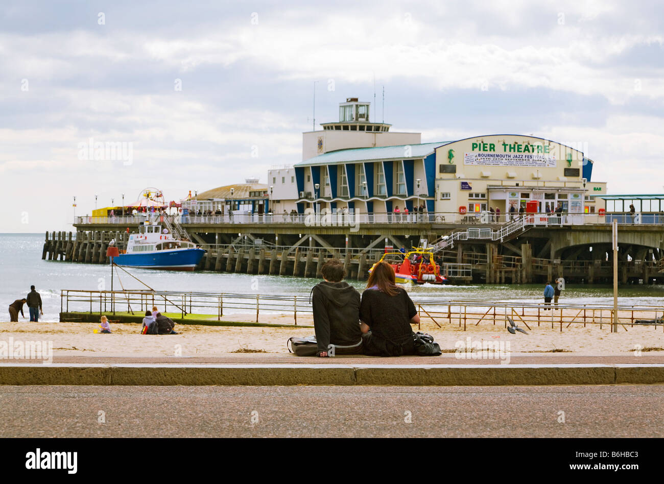 Junges Paar sitzt direkt am Meer in der Nähe von Bournemouth Pier, Dorset. UK Stockfoto