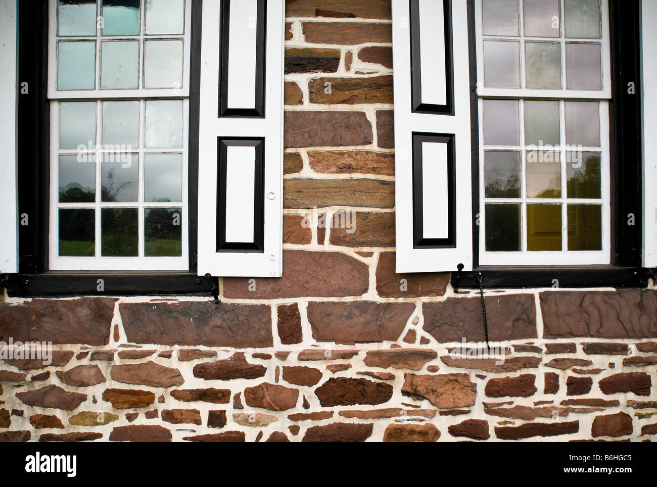 Zwei Fenster mundgeblasene Glasscheiben mit Fensterläden aus einem Bauernhaus Pennsylvanian Steinen. Stockfoto