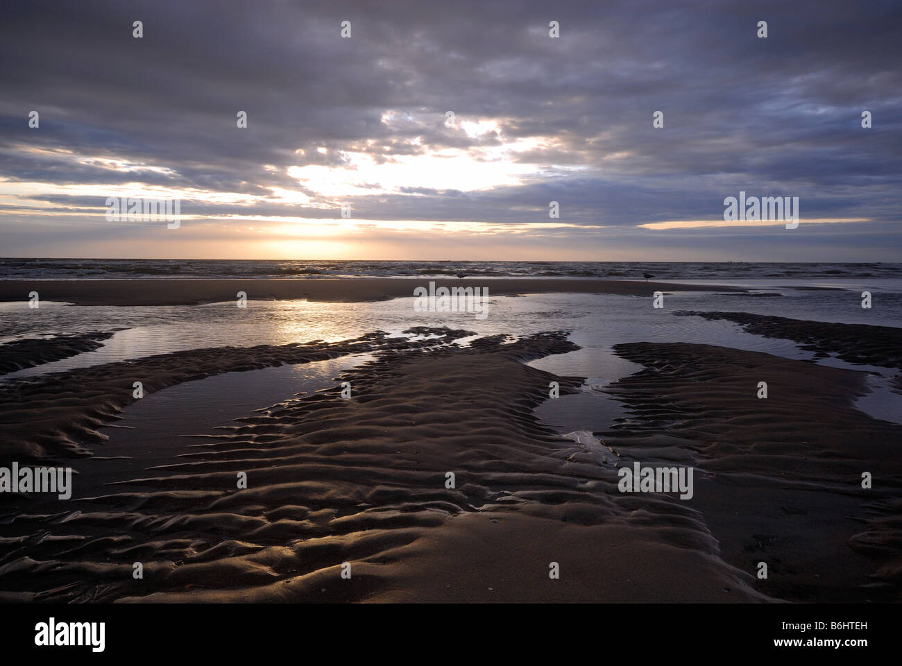 Sonnenuntergang und Wellen am Strand Stockfoto