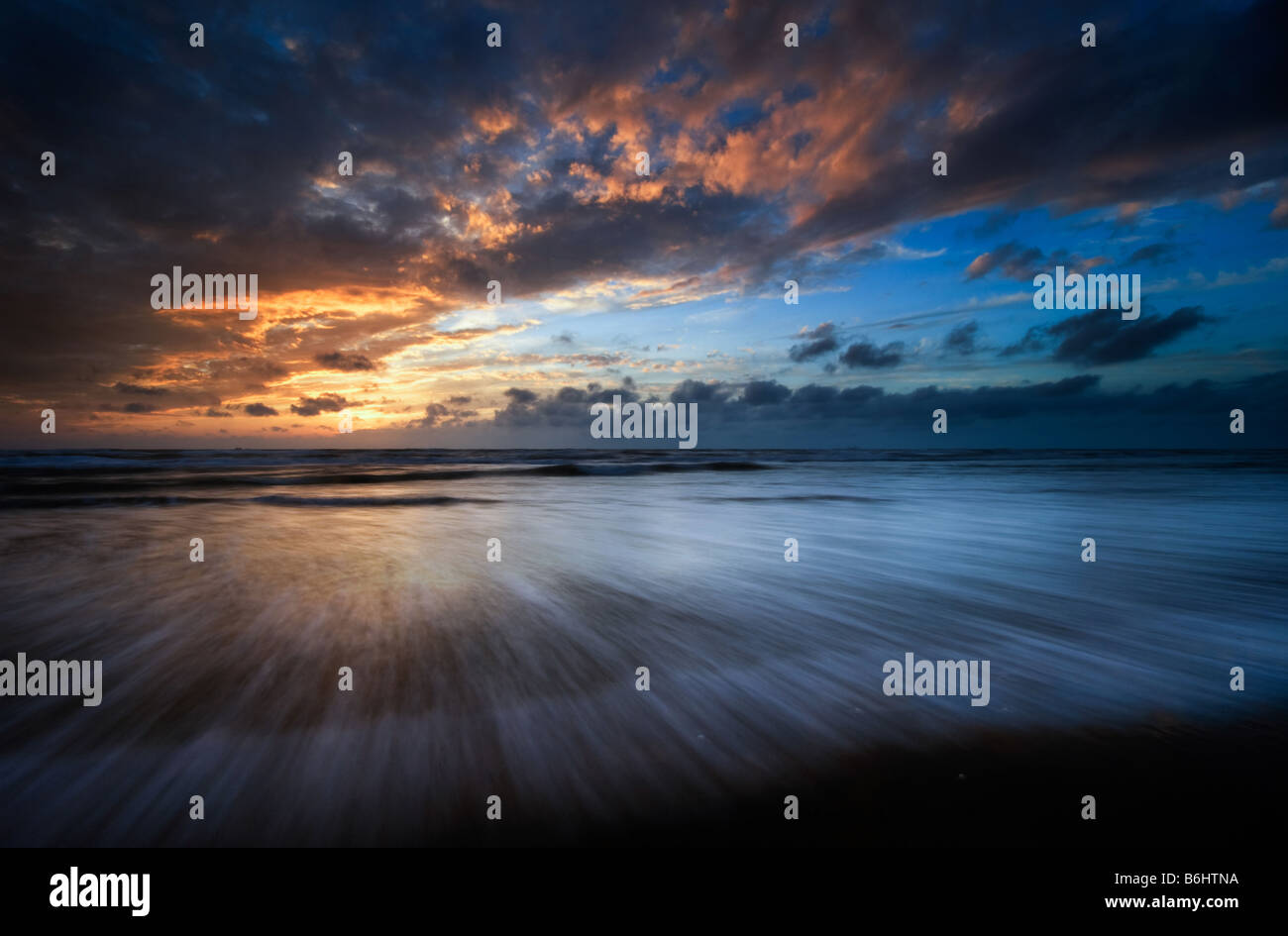 Sonnenuntergang und Wellen am Strand Stockfoto