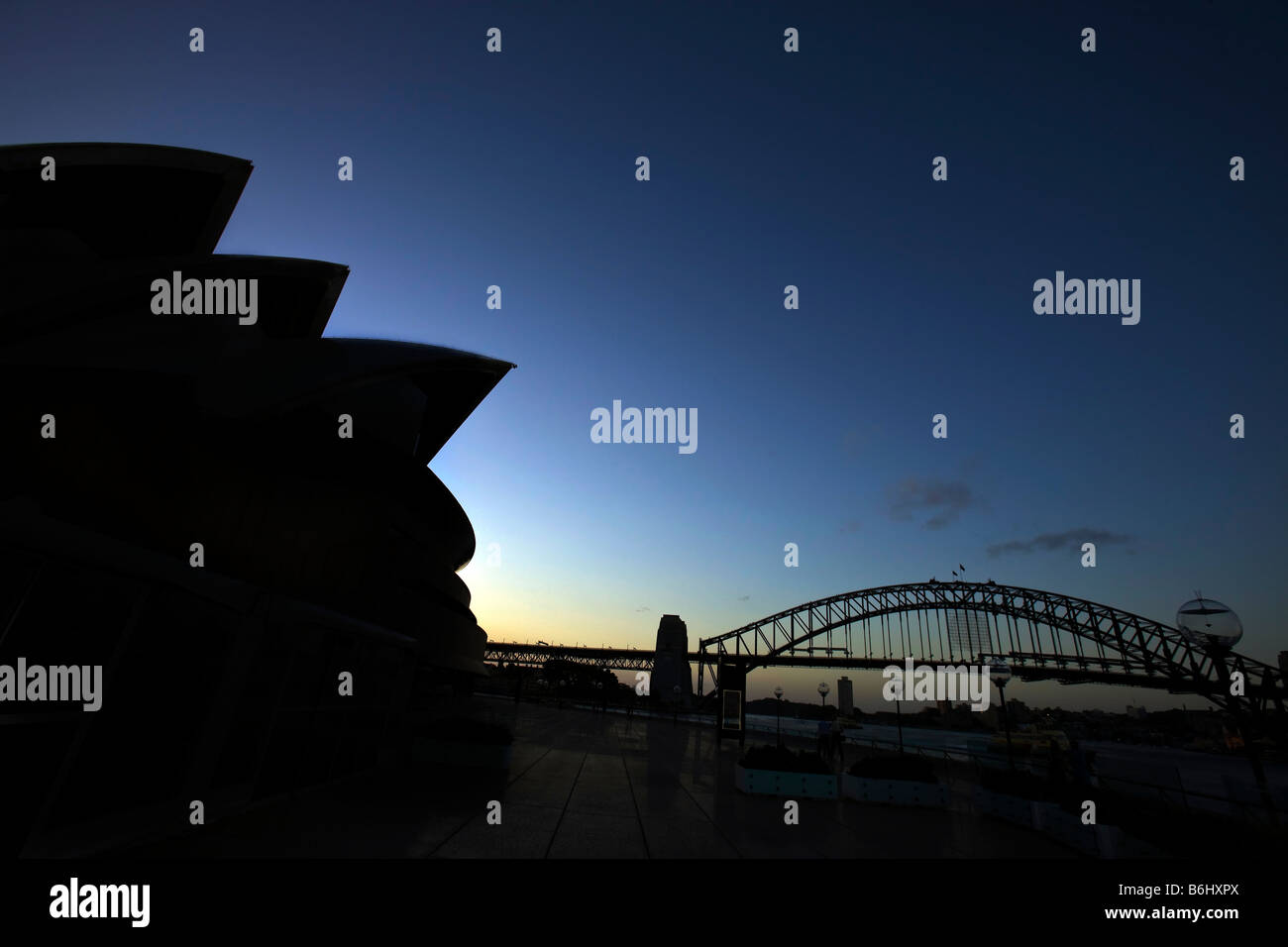 Silhouette des Sydney Opera House bei Sonnenuntergang mit Sydney Harbour Bridge im Hintergrund, Sydney, New South Wales, Australien Stockfoto
