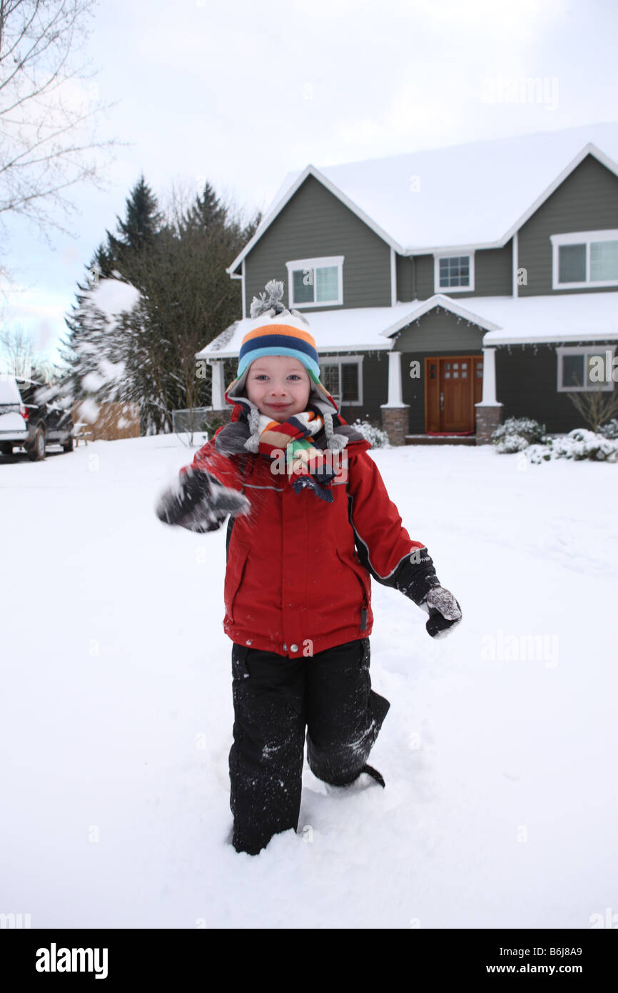 Kleiner Junge in Hof Kamera Schneeball bewerfen Stockfoto