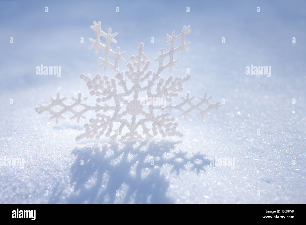 Schneeflocke Ornament Guss Schatten auf dem weißen Winterschnee Stockfoto