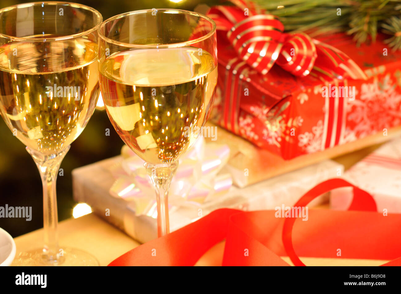 Weihnachts-Szene 2 Weingläser gefüllt mit Weißwein mit verpackte Weihnachtsgeschenke auf Tisch. Stockfoto