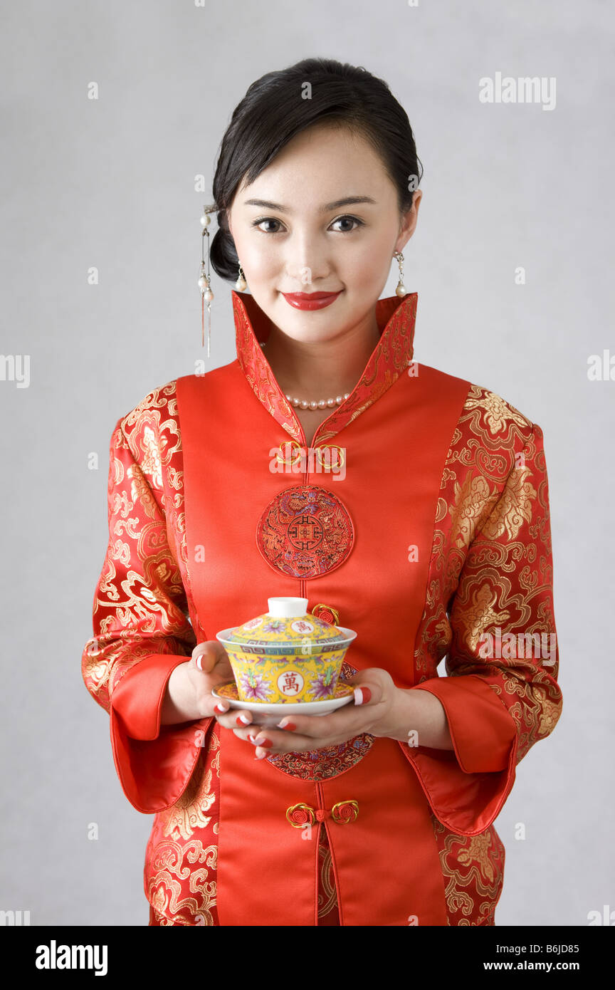 Junge Frau im Cheongsam hält eine Tasse Tee Stockfoto