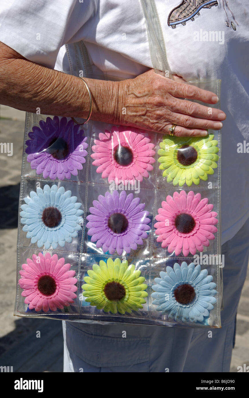 Nahaufnahme der Damen Hand auf klare leere Kunststoff Umhängetasche mit neun bunten individuellen Blumenmuster England UK Stockfoto