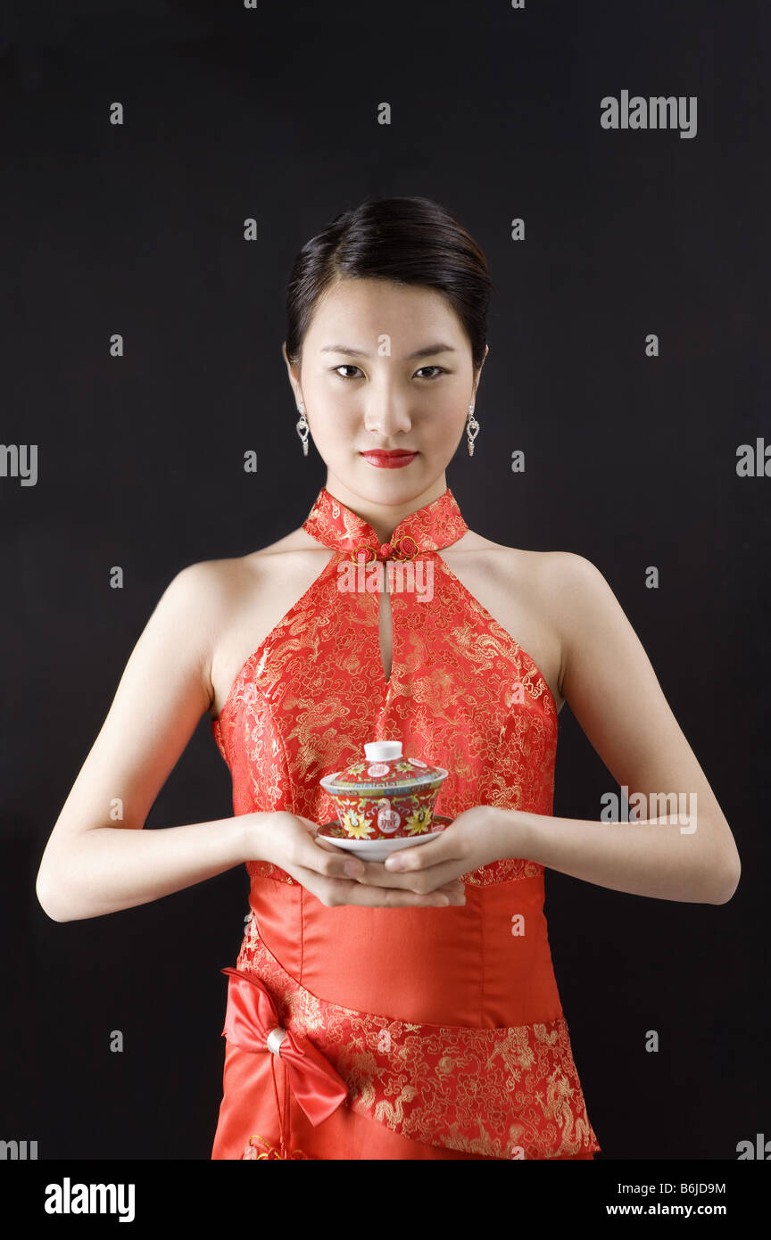 Junge Frau im Cheongsam hält eine Tasse Tee Stockfoto