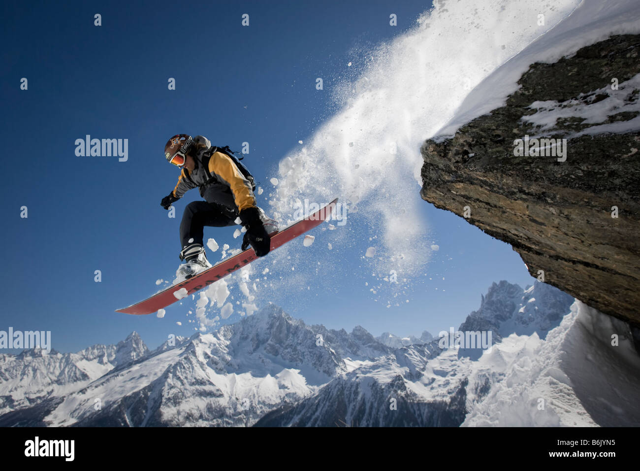 Ein Snowboarder springt von einem Felsen bei Le Brévent, Chamonix, Frankreich. Stockfoto